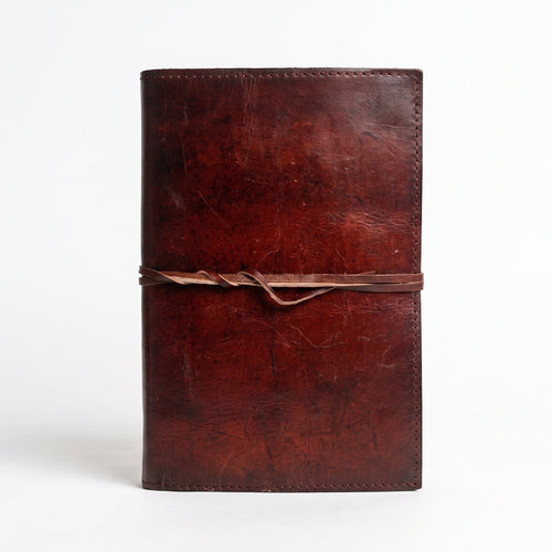 Retkatha cognac brown buffalo leather journal with a wrap-around strap closure and rustic hand-stitched finish.